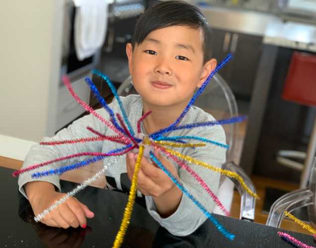 a child displays his sea urchin made from colored pipe cleaners