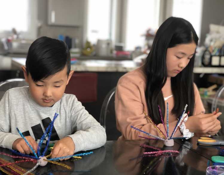 Two young people construct sea urchins from colored pipe cleaners