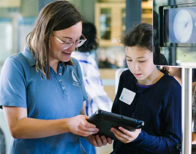 an educator talks with a young person while holding a tablet