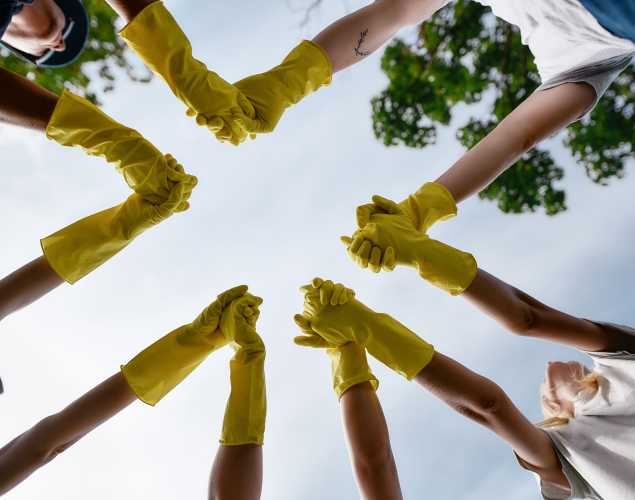 circle of young people wearing work gloves and holding hands