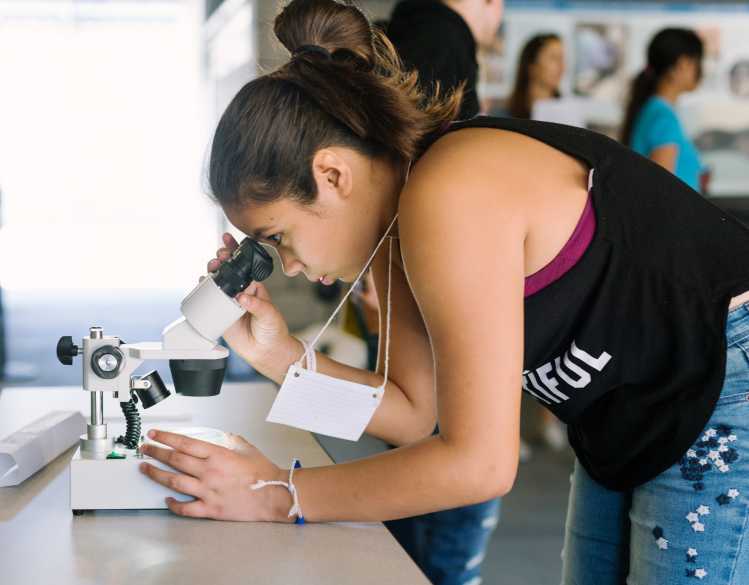 student looks into microscope