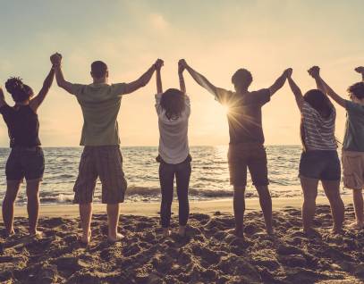 young people holding raised hands on the beach