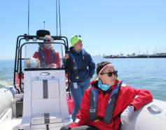 Three researchers on a boat looking for whales with Bekah Lane in the center