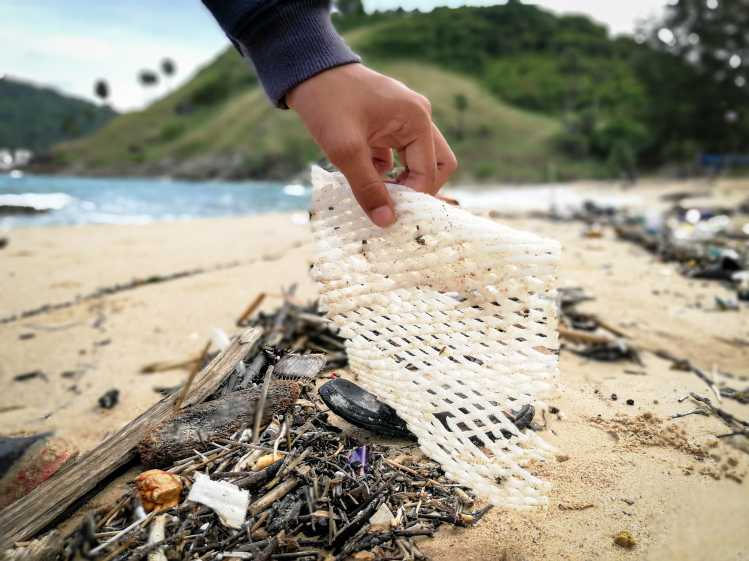 someone picks up plastic trash on a beach