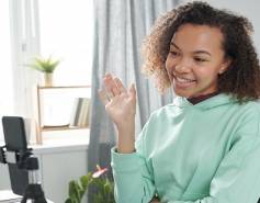 student smiling and waving at phone camera