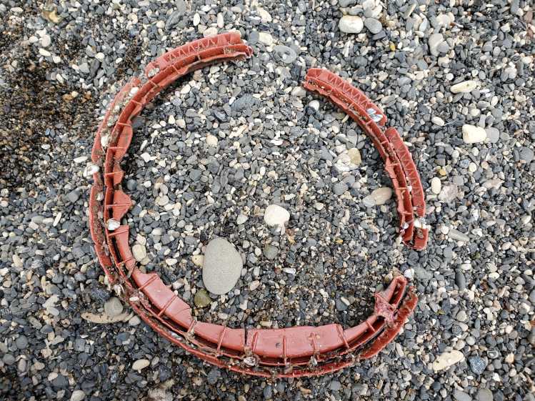 A broken red plastic bucket lid rim on top of rocks.