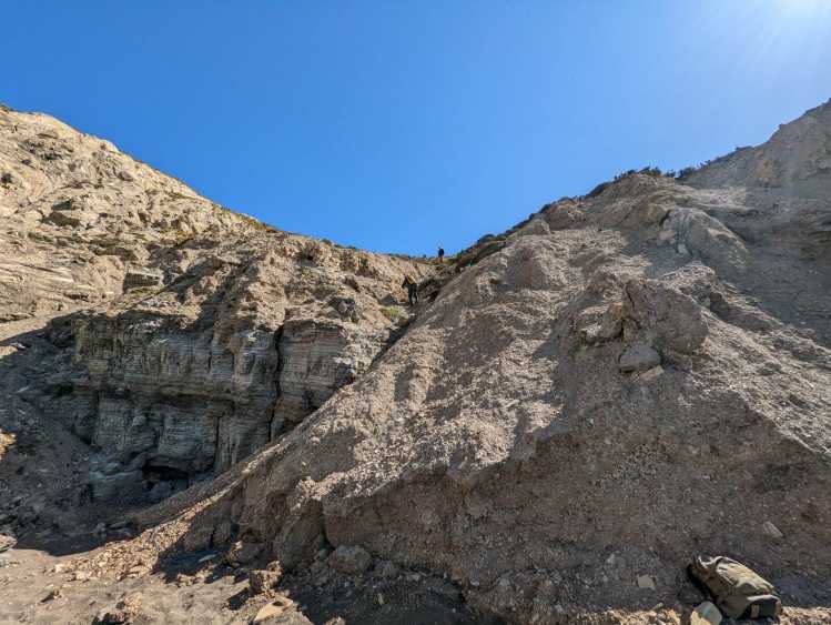 Researchers climb down tall rocky cliffs.